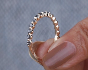 May include: A delicate gold band with a row of black diamonds set in a twisted design.