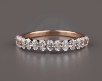 May include: A rose gold band ring with a row of oval-shaped clear gemstones.