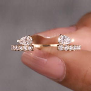 Anillo de compromiso MEG con tres piedras apilables de moissanita en forma de pera y diseño abierto, con plan de pago personalizado.