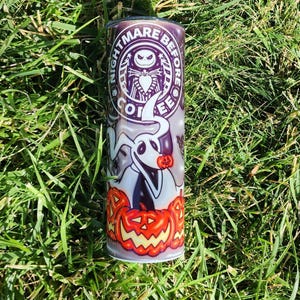 May include: A white stainless steel tumbler with a Nightmare Before Christmas design. The design features Jack Skellington, Zero the ghost dog, and pumpkins. The text "Nightmare Before Coffee" is printed on the tumbler.