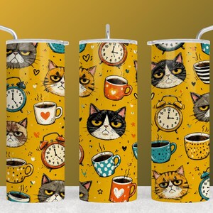 May include: Three cylindrical tumblers with straws, featuring a mustard yellow background patterned with illustrations of grumpy cats, analog alarm clocks, and coffee mugs. The design includes various cat faces, colorful mugs with hearts or dots, and clocks showing different times.
