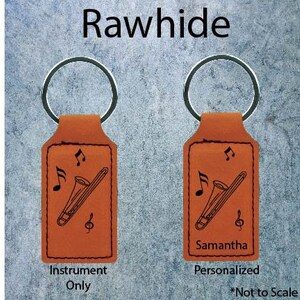 May include: Two brown leather keychains with a trombone design. One keychain has the word "Instrument Only" printed below the design. The other keychain has the name "Samantha" printed below the design and the words "Personalized *Not to Scale" printed below the name.