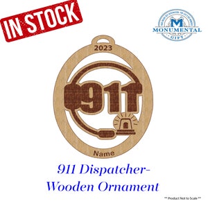 May include: Wooden 911 dispatcher ornament with the number 911 and a headset design. The ornament is light brown with darker brown accents and the year 2023. The words "IN STOCK" are in a red box.