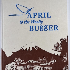 Può includere: Un libro vintage intitolato "April & the Woolly Bugger" con testo blu e un'illustrazione marrone. La copertina presenta una scena di montagna, un alce e altri animali selvatici. Il libro ha uno sfondo color crema.