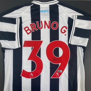 May include: A white and black striped soccer jersey with the name "BRUNO G." and the number "39" on the back. The jersey has the team logo and the text "NUFC" on the back.
