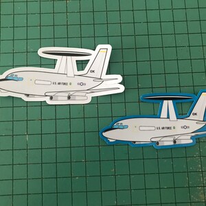 May include: Two white E-4B aircraft stickers with black and blue details. The stickers feature the text "U.S. AIR FORCE" and "OK".