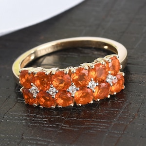 May include: A gold ring with a row of orange opals and small diamonds set in the band.