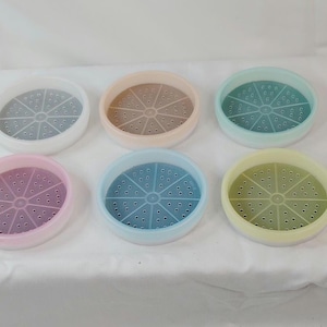 May include: Six colorful plastic steamer inserts in pastel shades: white, peach, mint green, pink, blue, and yellow. Each has a perforated center for steaming food. These kitchen tools are designed for use in a variety of cooking applications.