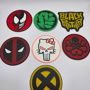May include: Eight round, colorful coasters with various superhero and cartoon character designs. The coasters feature images of Spiderman, Hulk, Black Panther, Deadpool, Punisher, Hydra, and X-Men.
