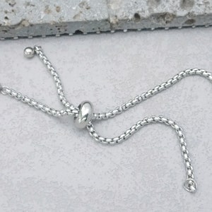 Op de afbeelding: Een zilveren kettingarmband met een schuifsluiting. De armband is gemaakt van een delicate ketting en heeft een eenvoudig, elegant ontwerp.