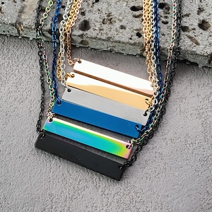 May include: Four layered necklaces with different colored bar pendants. The top layer is gold, the second is silver, the third is blue, and the bottom is iridescent.