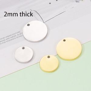 Könnte beinhalten: Drei runde Metallanhänger mit einem Loch oben. Die Anhänger sind 2 mm dick und in Silber und Gold erhältlich. Die Anhänger sind perfekt, um Ihren Bastelarbeiten eine persönliche Note zu verleihen.