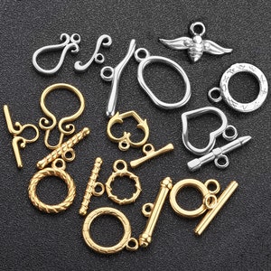 May include: Assortment of silver and gold metal clasps and connectors for jewellery making.  The clasps include a heart, a bee, a circle, and a variety of shapes.