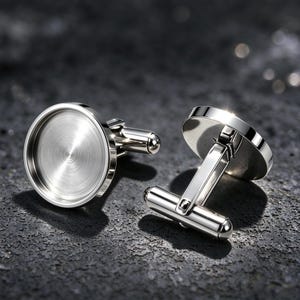 May include: Two silver-toned metal cufflinks featuring a circular, flat-bottomed bezel setting with a polished, reflective finish. Each cufflink has a hinged T-bar toggle mechanism on the back, designed for securing through buttonholes on a shirt cuff.