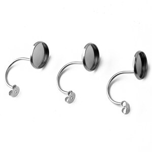 May include: Three silver earring settings with round, clear glass cabochons. The settings have a curved post and a butterfly back.