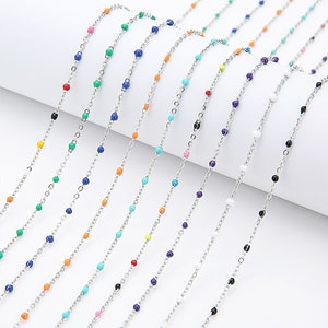 May include: A variety of colorful beaded chains, each with a different color bead, are displayed on a white surface. The chains are made of silver metal and are approximately 18 inches long.
