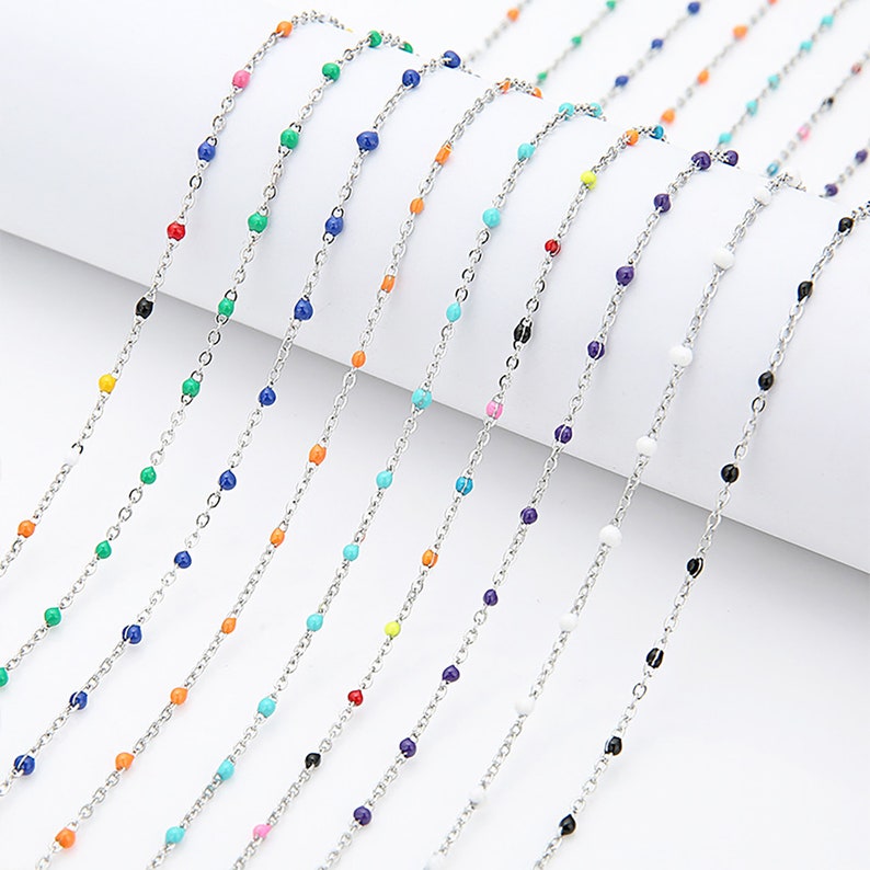 May include: A variety of colorful beaded chains, each with a different color bead, are displayed on a white surface. The chains are made of silver metal and are approximately 18 inches long.