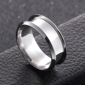 May include: A silver ring with a wide, flat band and a bevelled edge.