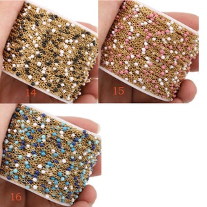 May include: Three spools of gold chain with small colored beads. The chains are black, pink, and blue.