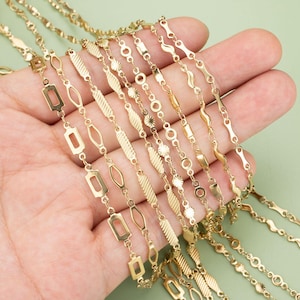 Può includere: Una collezione di catene in metallo dorato con diversi stili di maglie, tra cui maglie quadrate, rotonde e ondulate. Le catene sono esposte su una mano.