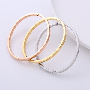 Op de afbeelding: Drie eenvoudige armbandjes in zilver, goud en roségoud. De armbandjes zijn gemaakt van metaal en hebben een gepolijste afwerking.