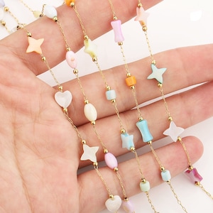 May include: A gold chain necklace with various pastel-colored shell beads in different shapes, including stars, hearts, and squares.