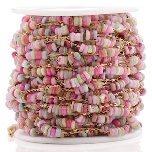 May include: A spool of gold chain with pastel pink, green, and white shell beads. The chain and beads are wrapped around the spool.