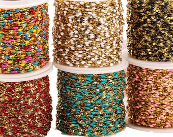May include: Six spools of gold-toned metal chain, each featuring small, evenly spaced beads in distinct colors: multi-colored, white, black, red, turquoise, and light pink. The chains are tightly wound around white plastic cylindrical spools.