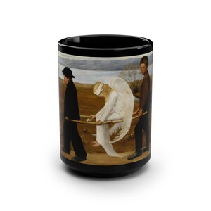 May include: A black coffee mug with a painting of an angel being carried by two people. The angel is wearing a white robe and has wings. The people are wearing dark clothing. The background is a landscape with a river and trees.