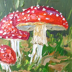 Puede incluir: Una pintura de setas rojas y blancas con tallos blancos que crecen en una zona verde cubierta de hierba. Las setas tienen manchas blancas en los sombreros rojos. La pintura est&aacute; firmada "ELVIRA SH" en la esquina inferior derecha.