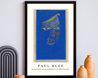 May include: A framed print of a painting by Paul Klee titled "Bildnis eines Asiaten (Portrait of an Oriental)" (1924). The painting depicts a stylized portrait of a person with a blue background and a yellow, green, and red face.