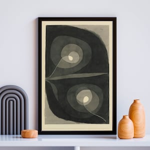 Puede incluir: Una impresión de arte abstracto en blanco y negro con un diseño enmarcado de círculos y líneas superpuestos. La impresión tiene un fondo beige claro.