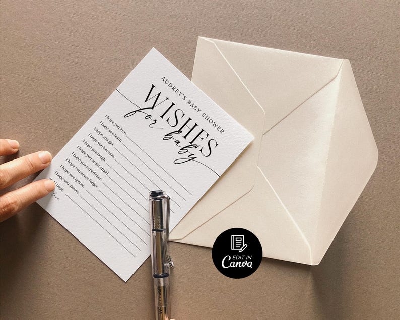 以下が含まれることがあります： 白いカードに黒い文字で「Audrey's Baby Shower Wishes for Baby」と書かれています。カードには、赤ちゃんへの願い事を書くための線が引かれています。カードの上にペンが置かれています。カードは白い封筒の上に置かれています。