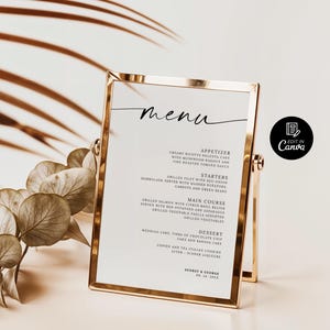 Op de afbeelding: Een goudomrand menu met een witte achtergrond, met het woord 'menu' in elegant schrift. Het menu bevat voorgerechten, voorgerechten, hoofdgerechten en desserts. De onderkant van het menu bevat de namen 'Audrey & George' en de datum '08.24.2025'.