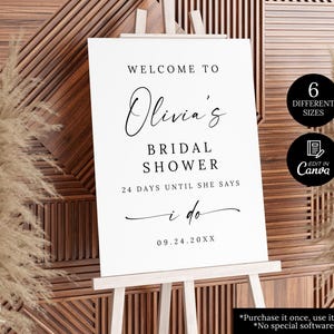 Puede incluir: Un letrero blanco sobre un caballete con las palabras "Welcome to Olivia's Bridal Shower" en escritura negra. El letrero tambi&eacute;n incluye el texto "24 d&iacute;as hasta que diga que s&iacute;" y la fecha 09.24.20XX. Dos c&iacute;rculos negros con texto blanco.