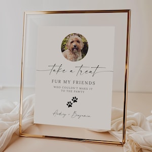 May include: A white sign with black text and a photo of a dog in a gold frame. The sign reads "take a treat FUR MY FRIENDS WHO COULDN'T MAKE IT TO THE PAWTY Audrey + Benjamin".