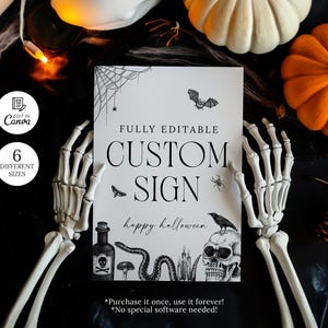 May include: A white sign with the text "CUSTOM SIGN" and "happy halloween" in black. The sign features illustrations of a bat, spider, raven, skull, and snake. The sign is held by a skeleton hand, with pumpkins in the background.