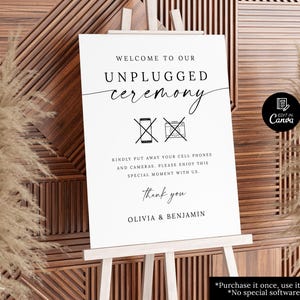 Puede incluir: Un letrero blanco sobre un caballete de madera con las palabras "WELCOME TO OUR UNPLUGGED ceremony". El letrero solicita a los invitados que guarden sus teléfonos móviles y cámaras. Los nombres Olivia y Benjamin están en la parte inferior. El letrero está frente a un fondo de madera.