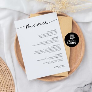 Op de afbeelding: Een trouwmenukaart met een minimalistisch ontwerp, met het woord "menu" in elegant schrift. Het menu bevat voorgerechten, voorgerechten, hoofdgerechten en desserts. De kaart ligt op een houten bord met een gouden envelop, met de tekst "Edit in Canva".