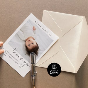 May include: A white thank you card with black calligraphy that reads "thank you" and "for your lovely gifts and kind wishes". The card features a photo of a baby lying on its back with its arms outstretched. The text "Olivia Anderson" is printed in the top right corner of the card.