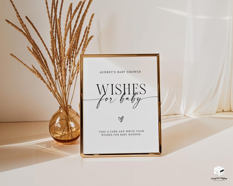 以下が含まれることがあります： 白い背景に黒い文字で「Audrey's Baby Shower Wishes for Baby Take a card and write your wishes for Baby Hanson.」と書かれた、金色の額縁の看板です。