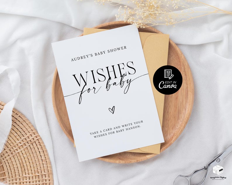 以下が含まれることがあります： 白地に黒文字で「Audrey's Baby Shower Wishes for Baby」と書かれたカード。ハートマークと「Take a card and write your wishes for Baby Hanson.」というテキストも書かれている。カードは木製の表面に置かれ、茶色の封筒と、白文字で「Edit in Canva」と書かれた黒い円形がある。