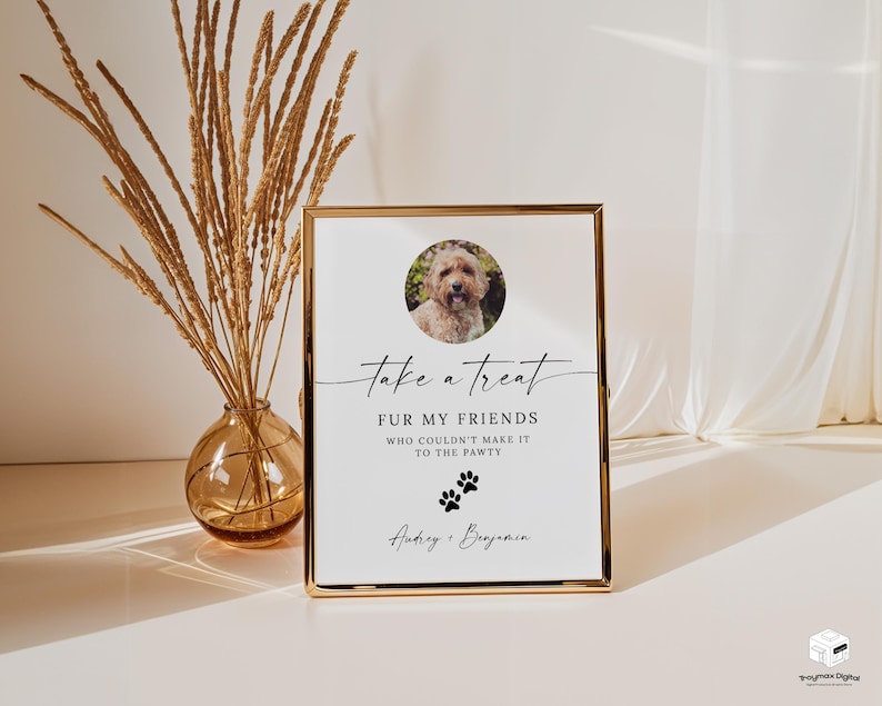 May include: A white sign with black text that reads "Take a treat fur my friends who couldn't make it to the pawty."  The sign has a photo of a dog in the top left corner and paw prints below the text. The sign is in a gold frame.