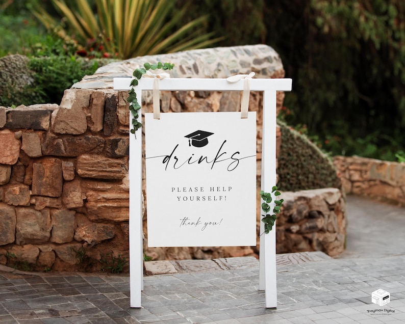 May include: A white wooden sign with the word "drinks" in elegant script, topped with a graduation cap icon. The sign reads "Please help yourself! Thank you!" and is decorated with greenery.