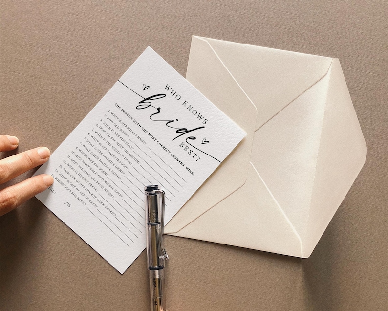 May include: A white card with black text that says "Who Knows the Bride Best?" with a list of questions about the bride. The card is on a beige surface with a white envelope.