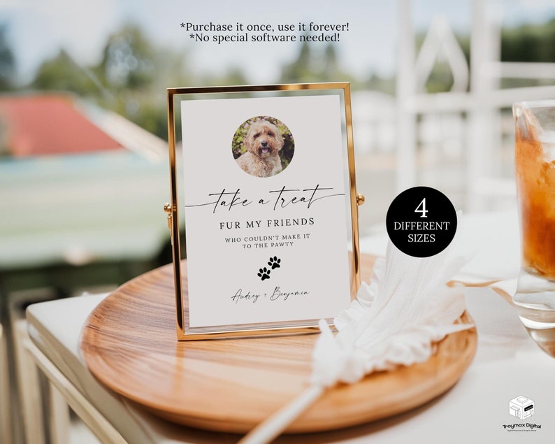 May include: A gold framed sign with a white background and black text that reads 'take a treat fur my friends who couldn't make it to the pawty' with a paw print graphic. The sign also has a photo of a dog in a circle. The text '4 different sizes' is in a black circle on a white background. The sign is on a wooden table with a white feather and a glass of brown liquid.