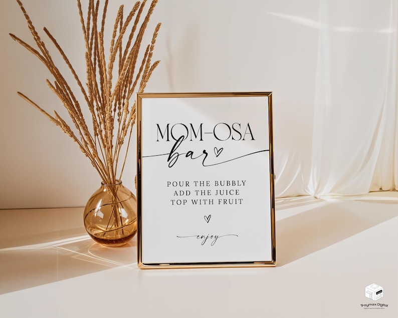 May include: A gold-framed sign with the text "MOM-OSA bar" in black cursive font. The sign also includes instructions for making a mimosa: "POUR THE BUBBLY ADD THE JUICE TOP WITH FRUIT" and the word "enjoy" in cursive.