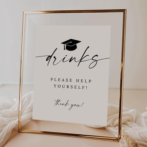 May include: A graduation-themed sign in a gold frame. The sign reads "drinks" in elegant script, with a graduation cap icon above it. Below, it says "PLEASE HELP YOURSELF!" and "thank you!" in a simple font. The background is a soft, neutral color.