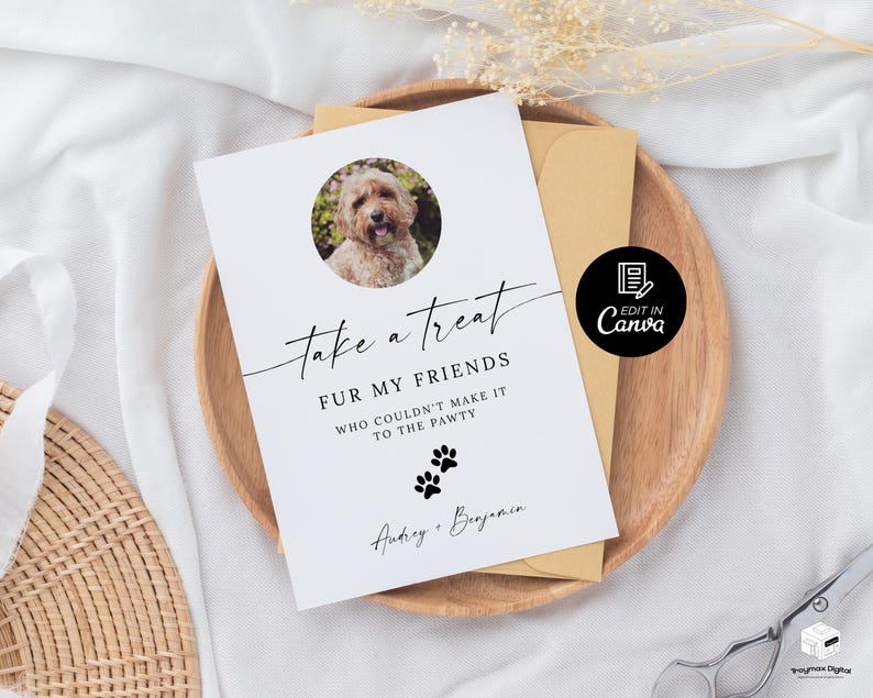 May include: White card with black text that reads "Take a treat fur my friends who couldn't make it to the pawty."  The card has a paw print graphic and a photo of a golden dog in a circle. The text "Anticy + Benjamin" is at the bottom of the card.  The card is on a brown wooden surface.
