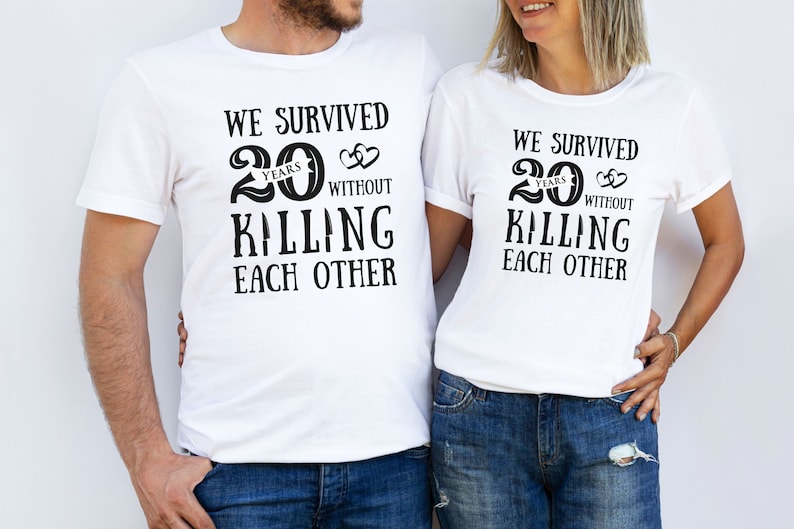 K&ouml;nnte beinhalten: Zwei wei&szlig;e T-Shirts mit schwarzem Text, der lautet "Wir haben 20 Jahre &uuml;berlebt, ohne uns gegenseitig umzubringen".